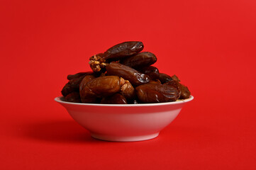 A plate with delicious fresh dates to break the fast in Ramadan. Red background, copy space.