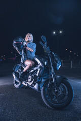 Fototapeta na wymiar portrait of a girl in the rays of neon light on a motorbike at night in an empty parking lot