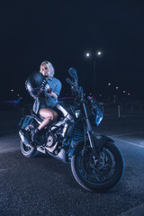 Plakat portrait of a girl in the rays of neon light on a motorbike at night in an empty parking lot