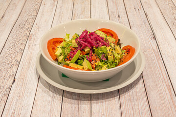 huge salad bowl with avocado and sweet corn, confit red onion, sliced tomato, escarole and sesame and poppy seeds
