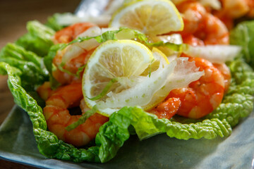 A dish of lettuce leaves, lemon and king prawns.