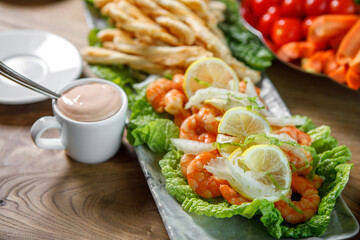 A dish of lettuce leaves, lemon and king prawns.