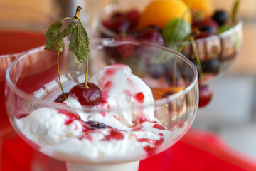 Ice cream in a glass glass, filled with sweet syrup, decorated with a cherry. Sweet dessert.