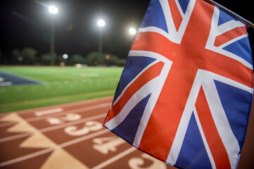 Floodlit view of Union Jack flag flying in front of the numbered lanes at the starting line of a...