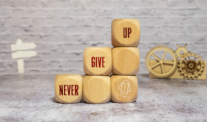 never give up, word cube on wood background,