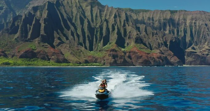 Epic jet ski adventure, young couple riding jet ski in front of amazing tropical island sea cliffs, vacation lifestyle