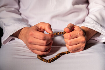 Muslim man holding rosary after pray  wearing dishdash