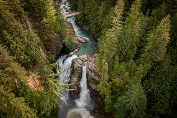 Aerial View of Nooksack Falls seen in the Cascade Mountains of Washington state. The water flows through a narrow valley and drops freely 88 feet into a deep rocky river canyon.  - 445800147
