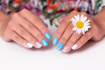 Female hands with summer manicure nails, decorated with camomile flowers