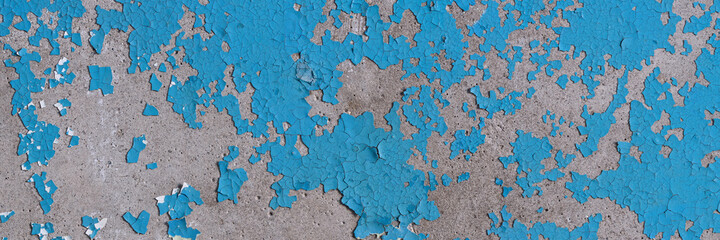 Peeling paint on the wall. Panorama of a concrete wall with old cracked flaking paint. Weathered rough painted surface with patterns of cracks and peeling. Wide panoramic texture for grunge background