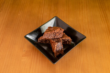 Pieces of chocolate brownie cake with walnuts inside a black square bowl