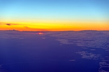 Fototapeta na wymiar View from the plane at sunrise. Flying above the clouds