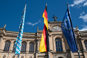 Fototapeta na wymiar Bavarian, German and European Union flags in front of the Maximilianeum / Bavarian State Parliament building in Munich, Germany