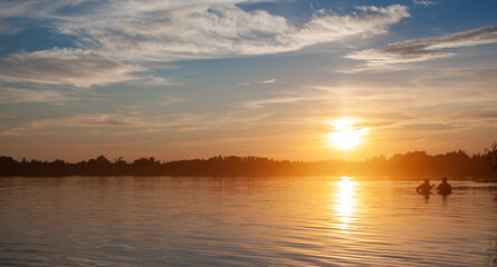 Fototapeta premium Colorful sunny sunset on a calm lake. The sun is reflected on the surface of the water.
