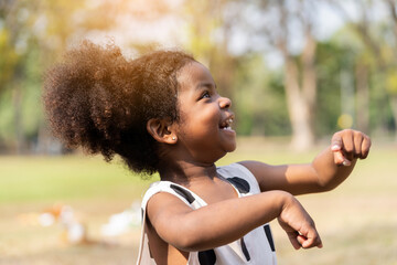 Cheerful African American toddler little girl playing outdoor in the park. Cute black people child...
