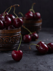 Organic juicy cherry in a bowl on dark background. Close-up photo, low key, selective focus