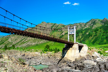 old steel suspension bridge over mountain river