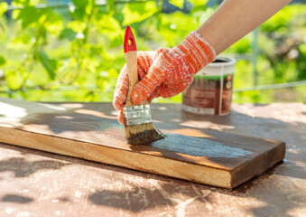 A woman in work gloves covers a board with decorative impregnation