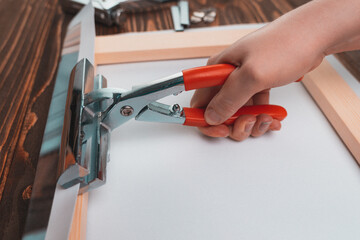 Hand with a tool for stretching the canvas. The business of producing paintings on canvas from photographs. Selective focus