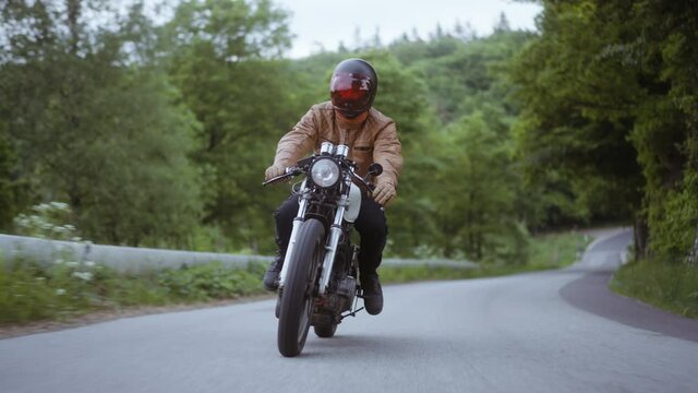 Tracking Shot of a Motorcycle on a Narrow Road  Surrounded by Lush Forest Trees