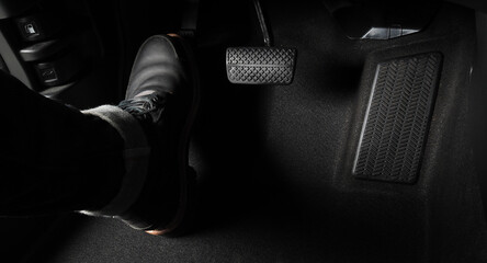 Man foot and accelerator and brake pedal inside the car or vehicle and copy space which black color leather shoe stepped on it for speed up or control automobile pace power. Automobile Driving concept - obrazy, fototapety, plakaty