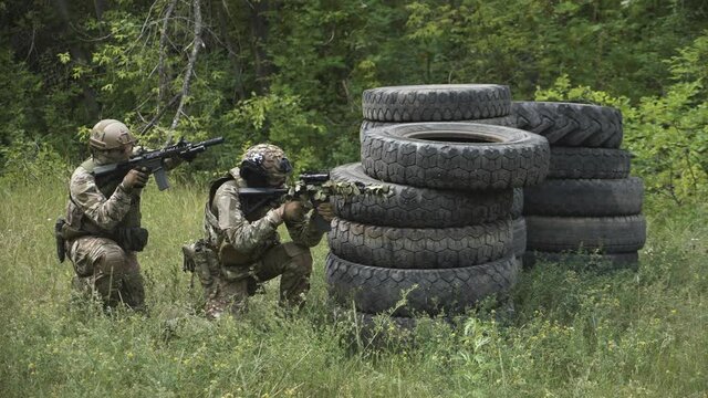 This stock footage shows a special forces unit on a mission in an open area. The military is fully equipped, with weapons in hand. The capture of a detached building is carried out.