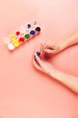 A girl paints eggs for Easter pink background