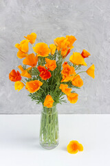 Bouquet of bright orange flowers in vase on background gray stone wall. Template for postcard. Concept Women's day, Mothers Day, Hello summer or Hello spring