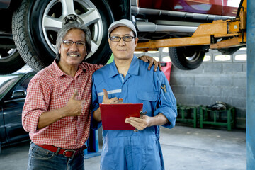 Customer heck the neck of automotive technician with smiling and look at camera also show thumbs up.