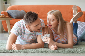 Young couple eating tasty chocolate at home