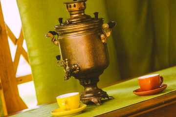 Russian copper samovar and tea cups on the table in the gazebo
