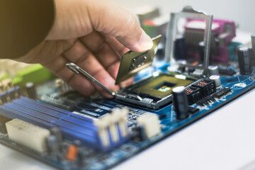 A young man is using his hand to pick up a PC computer CPU on a motherboard with many zips to upgrade a new CPU.