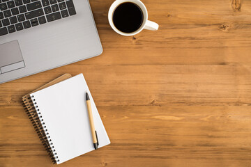 Top view photo of laptop cup of drink and pen on two spiral notebooks on isolated wooden table background with blank space