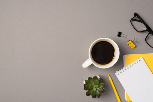 Top view photo of cup of coffee plant glasses binder clips yellow pencil and copybooks on isolated grey background with blank space
