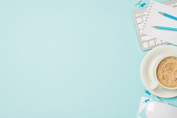 Top view photo of keyboard mouse notepad blue pencils pins and cup of frothy coffee on saucer on isolated light blue background with copyspace