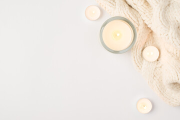 Top view photo of lighted candles and white knitted scarf on isolated white background with copyspace