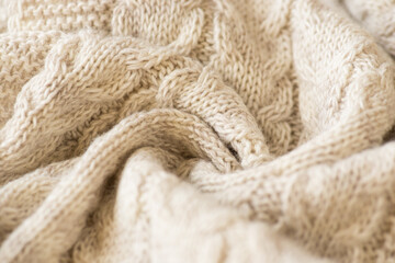 Closeup photo of crumpled knitted beige fabric with pattern