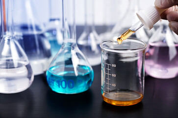Scientist or medical in lab coat holding test tube with using reagent with drop of color liquid over glass equipment working at the laboratory, Biochemistry laboratory research.	