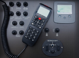 Black dashboard on a motor yacht with control buttons and a radio station, close-up. Walkie-talkie in the control cabin of a motor yacht. Radio station on a yacht.