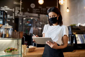Female cafe owner, entrepreneur using digital tablet. Small business.