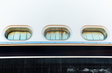 Hull of a luxury motorized white yacht with portholes, bottom view.