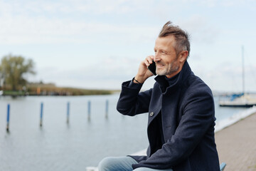 Attractive middle-aged man chatting on a mobile at the seaside