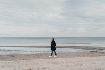 Lone man walking along a beach in winter