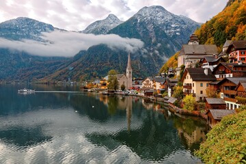 Early morning view of Hallstatt, a charming lakeside village in Salzkammergut region of Austria, with reflections on smooth lake water in colorful autumn season ~ A beautiful UNESCO heritage site