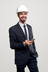 Smiling engineer in hardhat using smartphone