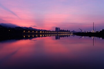 Fototapeta premium Beautiful Keelung River in morning twilight, with cable-stayed Dazhi Bridge in background and riverside street lamp lights under dramatic dawning sky reflected in peaceful water in Taipei City,Taiwan