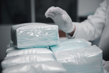 Close-up operator hand in glove packing medical mask to plastic bag packaging at production factory