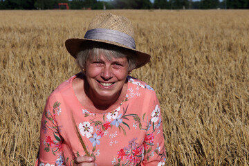 frau mit strohhut inmitten eines gerstenfeldes