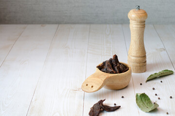 Jerky meat on a wooden background. Dried beef. Rustic style. Wooden dishes. Copy space. Close-up. Flat lay.