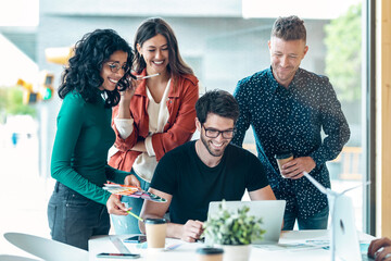 Successful business team standing around computer for presentation of work in the coworking space.